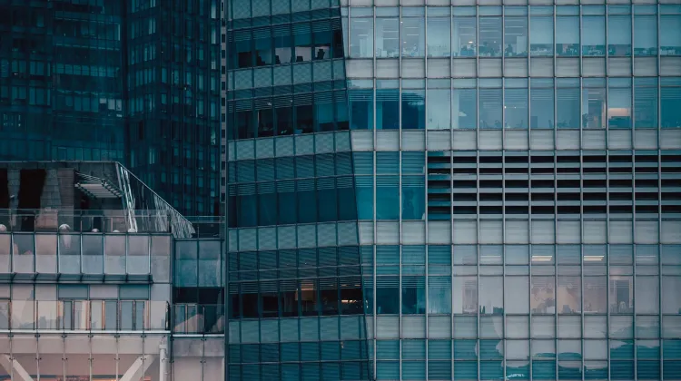 Close-up of modern buildings: blue and grey glass facades, many windows, and reflective surfaces.